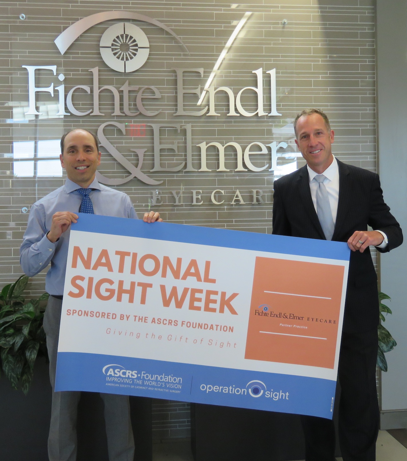 From left, Michael Endl M.D. and Thomas Elmer Jr. M.D. pose with the National Sight Week banner. (Photo by David Yarger)